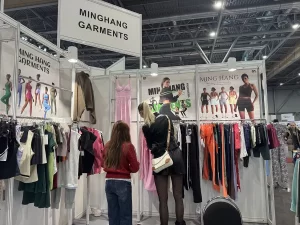 Visitors reviewing custom apparel samples at the Minghang Garments booth.