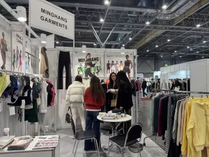 Visitors reviewing custom apparel samples at the Minghang Garments booth.